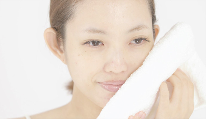 洗顔後にタオルで顔を押さえている女性